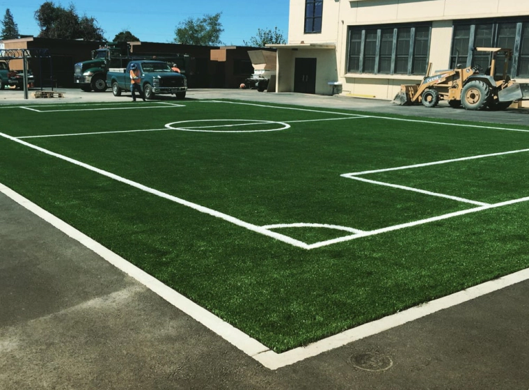 soccer field with green turf and some trucks around